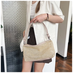 Detail of woven straw tote bag with pink leather handles and knot design on shoulder strap