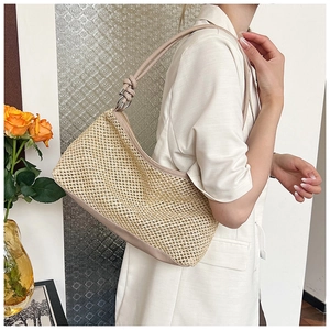 Detail of the woven beige tote bag featuring knotted leather shoulder straps and metal buckle