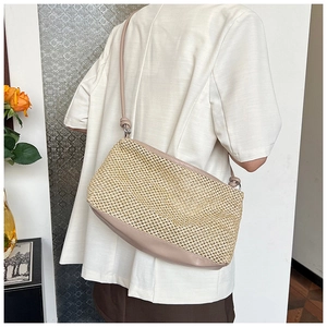 Close-up of contrast straw woven shoulder bag with faux leather strap in a home setting