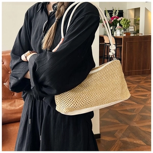 Detail of hand-woven straw tote with white leather trim and twisted knot shoulder strap