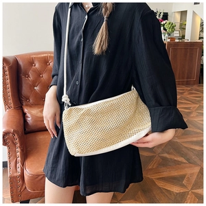 Detailed close-up of natural woven texture and white leather trim on straw tote bag