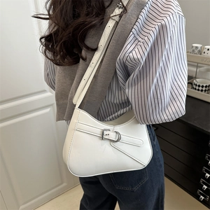 Elegant white crescent saddle bag with silver buckle shown on a model in a modern room
