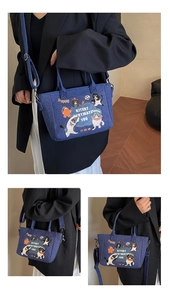 Detail of denim tote bag showing cute cartoon cat and dog illustrations with blue shoulder strap