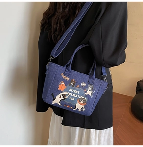 Detail of blue denim tote bag with cat illustration and adjustable shoulder strap