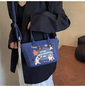 Close-up of blue denim tote bag with cute cartoon cat print and dual handles for women