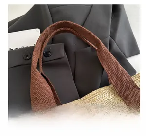 Detail showing handwoven beige straw texture with thick brown woven fabric handles