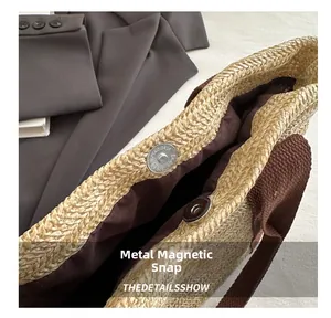Detailed macro view of the metal magnetic buckle and brown fabric lining on a straw bag