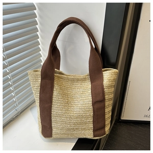 Detailed view of beige woven straw tote with contrasting dark brown canvas handles