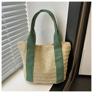 Close-up of woven straw tote bag with vibrant green cotton straps and detailed texture