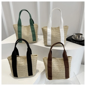 Detailed view of woven straw tote bags with colorful thick handles on white pedestals