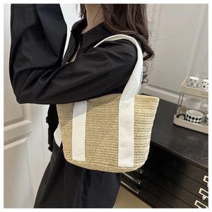 Detail of hand-woven straw tote bag with white canvas handles for casual summer styling