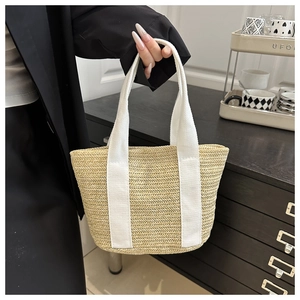 Detail of hand-woven straw tote bag with wavy texture and durable white fabric handles