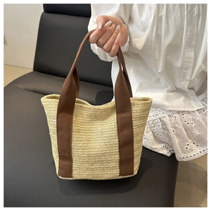 Detail of woven straw tote bag with brown canvas straps for summer beach or commute