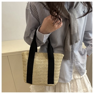 Detail of hand-woven straw bag texture with black canvas handle for summer styling