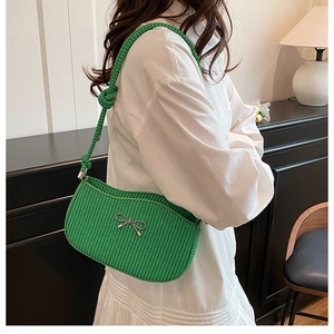Detailed macro view of vibrant green woven shoulder bag with silver metal bow accent