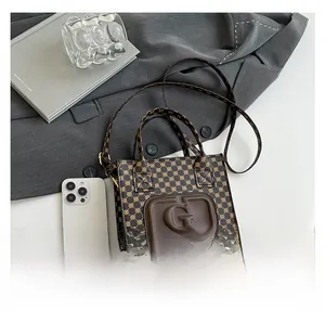 Mini brown monogram tote bag with leather G logo compared to a smartphone for size detail