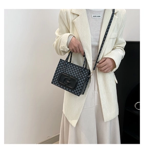 Detail of the blue monogram pattern and 3D letter G emblem on the black crossbody bag