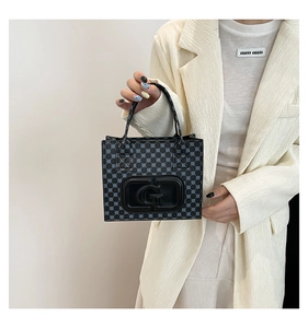 Detail of printed tote bag with G pattern shown on a model in cream blazer