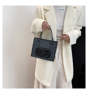 Detail of square black handbag with blue polka dots and embossed G logo on leather