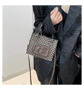 Detail of a brown vintage tote bag featuring an embossed G letter and classic pattern