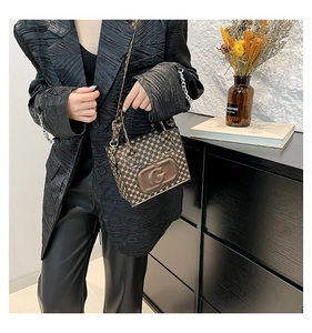 Close-up of vintage brown tote bag featuring detailed geometric monogram and 3D G logo
