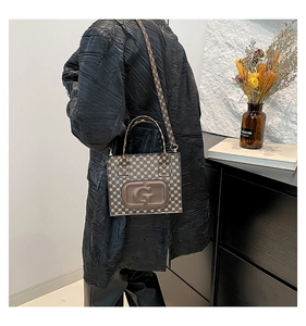Detail view of a vintage monogram crossbody bag with an embossed G logo and adjustable strap