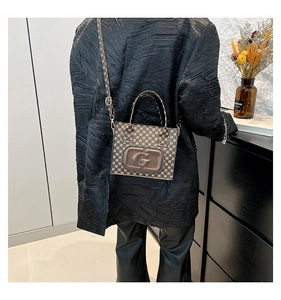 Detail shot of vintage brown monogram crossbody bag with large G embossed logo on model