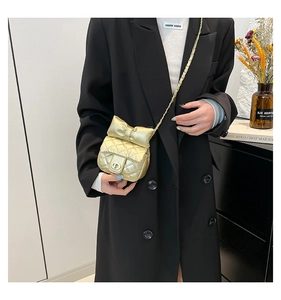 Detail van gouden gewatteerde mini-crossbodytas met strik gedragen door een model in pak