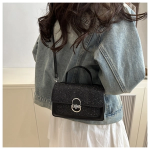 Détail d'un sac bandoulière noir avec rabat pailleté argenté et fermoir métallique