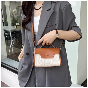Vue latérale d'un sac bandoulière tissé bicolore avec rabat en cuir marron porté par femme