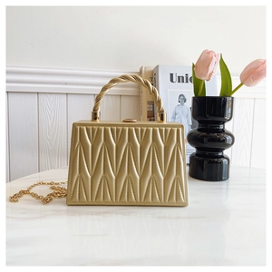 Detail of gold quilted evening bag with metal handle and delicate chain strap