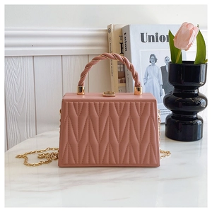 Close-up of pink quilted box bag with V-shaped texture and gold metal chain strap