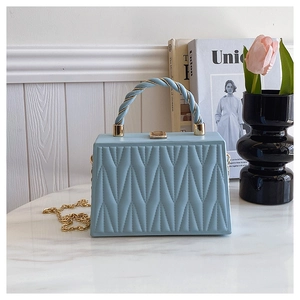Detail of light blue matelassé leather crossbody bag with gold chain and silk scarf