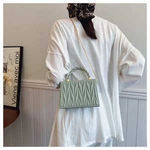 Chic mint green pleated crossbody bag with V-quilted texture and gold chain on model