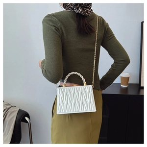 Rear view of a model wearing a white quilted crossbody bag with a gold chain strap