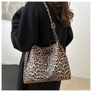 Detail of leopard print tote bag with knotted strap on model in black coat