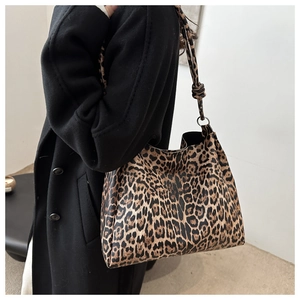 Detail of vintage leopard print tote bag styled with a long black coat for daily commute