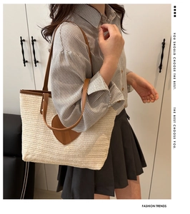 Détail du sac seau en paille tressée avec patch cœur marron et garniture en cuir sur modèle