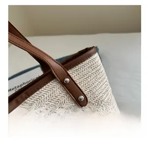Détail du sac fourre-tout en paille montrant la texture en V et l'anse en cuir brun