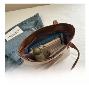 Détail intérieur du grand sac en paille contenant une tablette, un livre et des objets