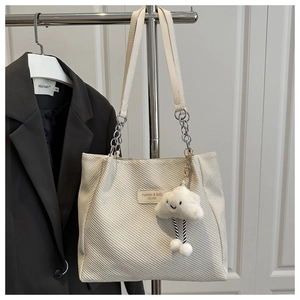 Detailed texture of beige canvas tote bag featuring silver chain strap and cloud charm