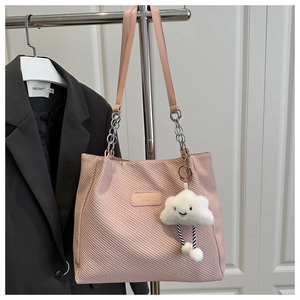 Detail of pink twill tote bag with gold logo plate and plush cloud charm accessory