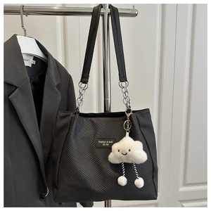 Detail of black tote bag with silver chain strap and a cute cloud plush charm