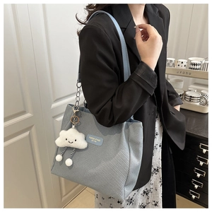 Detail of light blue tote bag with plush cloud charm and striped legs on a shoulder strap