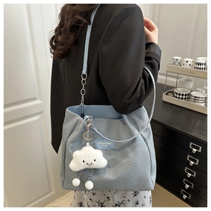 Detail of light blue corduroy tote bag with plush cloud charm and fashion patch