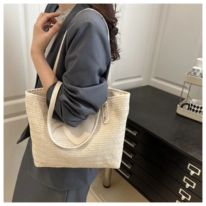 Détail d'un sac à bandoulière en paille beige avec lanières en cuir et rivets argentés