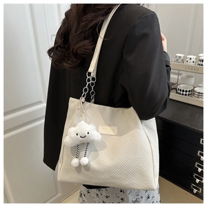 Detail of off-white corduroy tote bag with silver chain strap and cloud plush charm