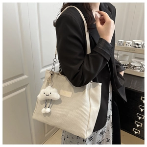Detail view of cream textured tote bag with chain strap and cute cloud charm accessory