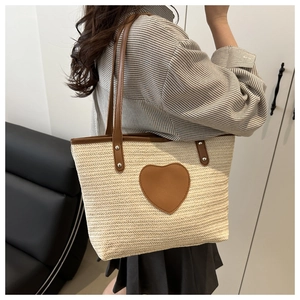 Détail du patch en cuir en forme de cœur sur un sac cabas en paille pour femmes
