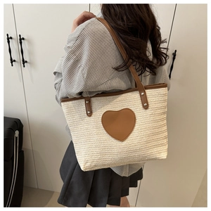 Vue détaillée d'un sac cabas tissé beige avec patch cœur marron porté par un mannequin